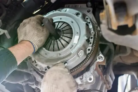 Mechanik w rękawiczkach naprawia sprzęgło samochodowe.